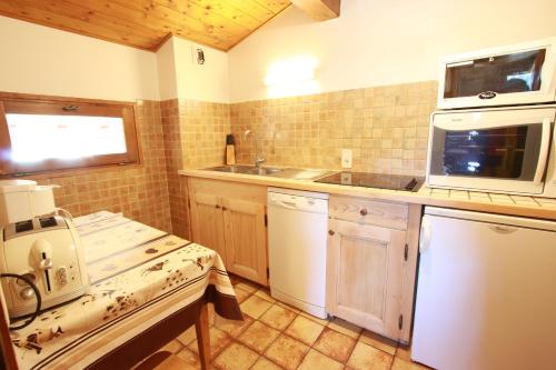 une cuisine avec un évier, une cuisinière et un micro-ondes dans l'établissement Chez Francine, à Notre-Dame-de-Bellecombe