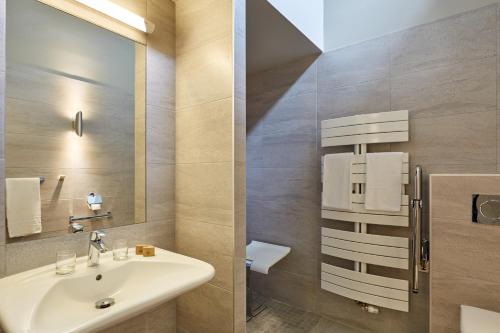 a bathroom with a sink and a mirror at Hôtel Centre Port-Royal in Saint-Lambert