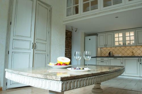 Una cocina con una mesa con un bol de fruta y copas de vino. en Provence Home, en Vilna