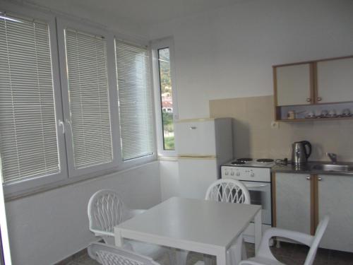 a kitchen with a table and a white table and chairs at Apartmani Stojanović in Sutomore