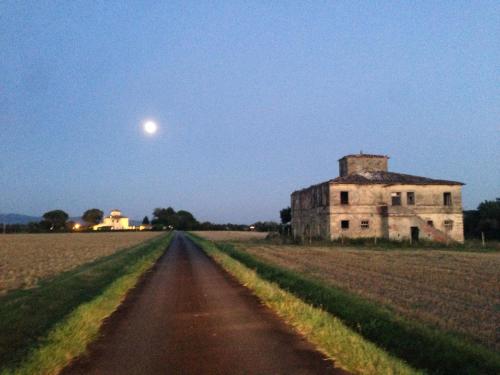 an old building in the middle of a field with the moon at Agrisalotto in Cortona