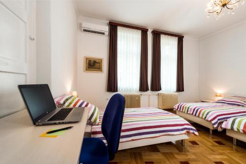 a room with two beds and a laptop on a desk at Vila Regina rooms in Karlovac