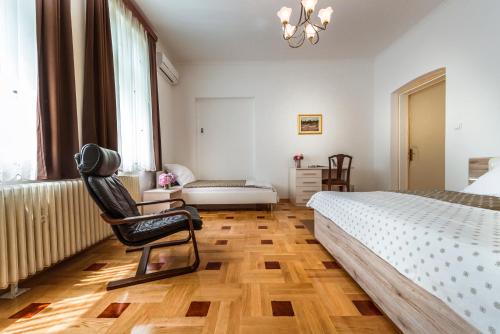 a bedroom with a bed and a chair in it at Vila Regina rooms in Karlovac