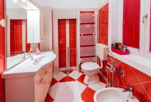 a red and white bathroom with a toilet and a sink at Vila Regina rooms in Karlovac