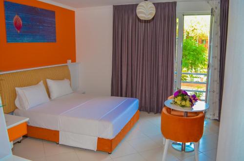 a bedroom with a bed and a table with a plate of food at Hotel Monaco & Garden in Golem