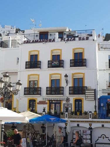 a large white building with windows and tables and umbrellas at Salamandra Plaza in Cómpeta
