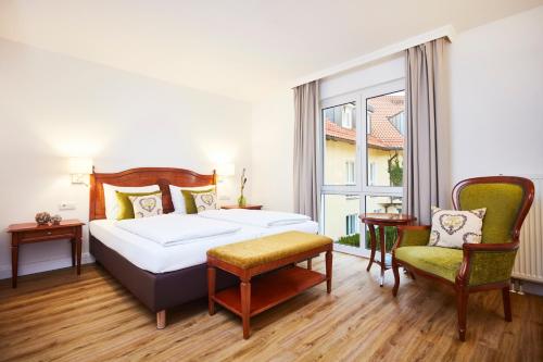um quarto com uma cama, 2 cadeiras e uma janela em Hotel Prinzregent München Messe em Munique