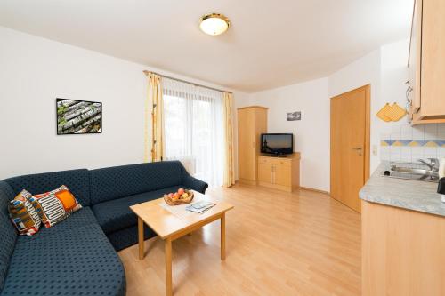 a living room with a blue couch and a table at Pension Niederreiter in Maria Alm am Steinernen Meer