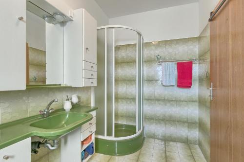 y baño con ducha y lavabo verde. en Apartments Veruda Porat, en Pula