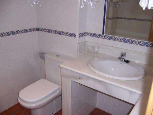 een witte badkamer met een wastafel en een toilet bij Pensión Os Ancares in Becerreá