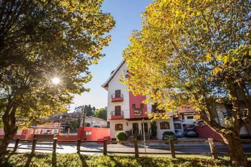 a pink and white building with trees in the foreground at Pousada Big Bear in Campos do Jordão