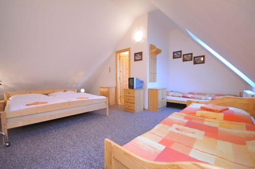 a attic bedroom with two beds and a tv at Penzión Anna Pieniny in Spišská Stará Ves