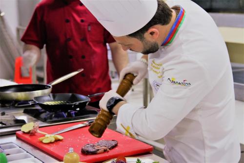 a chef preparing food on a red cutting board at Spring Hotel in Novxanı