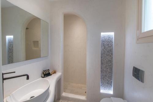 a white bathroom with a sink and a mirror at Iphimedeia Luxury Hotel & Suites in Naxos Chora