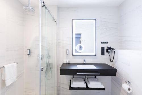a white bathroom with a sink and a shower at Grand Ascot Hotel in Kraków