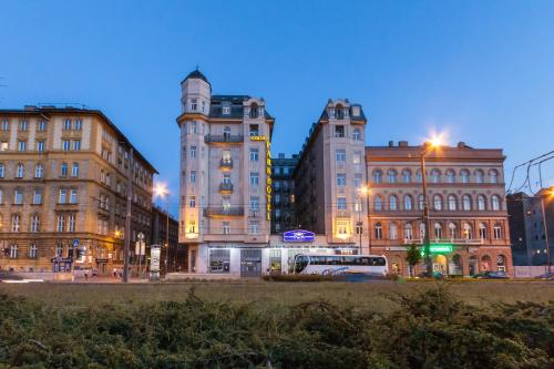 a city at night with buildings and a bus at Hotel Golden Park Budapest in Budapest