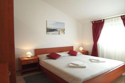 Un dormitorio con una cama con almohadas rojas y una ventana en Apartment Pokrajac, en Rovinjsko Selo