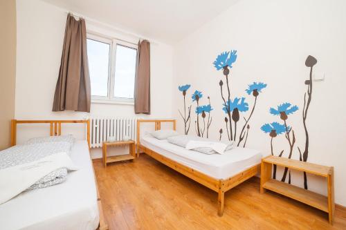 two beds in a room with blue flowers on the wall at Patio Hostel in Bratislava