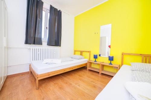 a bedroom with two beds and a yellow wall at Patio Hostel in Bratislava