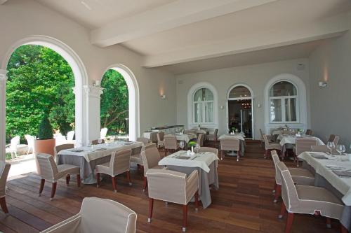 a restaurant with white tables and chairs and windows at HVD Boutique Hotel Oasis - Private Beach & Free Parking in Golden Sands
