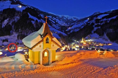 a small church with snow on it in front of a town at Appartements Wirnsperger in Grossarl