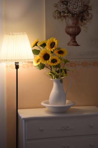 a vase filled with sunflowers on a table next to a lamp at Luciano And Son in Campobasso