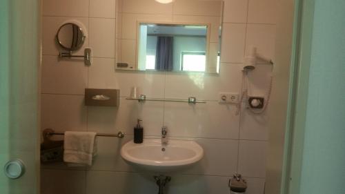 a bathroom with a sink and a mirror at Cityhotel Ahlen Garni in Ahlen
