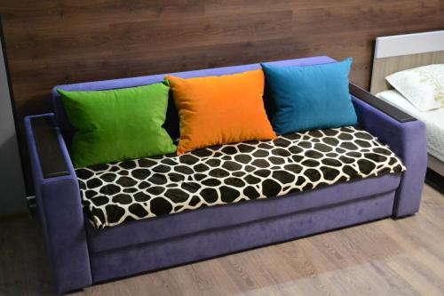eine lila Couch mit verschiedenen farbigen Kissen darauf in der Unterkunft Хай-Тек апартаменты в центре по Гоголя51 in Qaraghandy