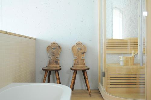 two wooden stools in a bathroom with a mirror at Apartments Etruska in Santa Cristina in Val Gardena