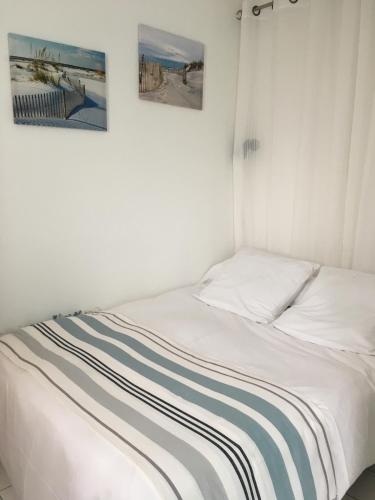 a bed in a room with two pictures on the wall at residence parc de pontaillac in Vaux-sur-Mer
