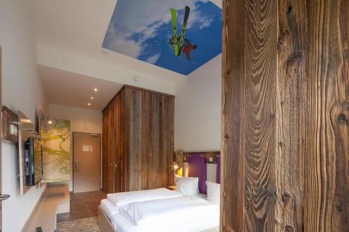a bedroom with a bed and a wooden wall at Explorer Hotel Hinterstoder in Hinterstoder