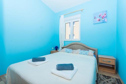 ein blaues Schlafzimmer mit einem Bett mit Handtüchern darauf in der Unterkunft Apartman Anamarija in Trogir