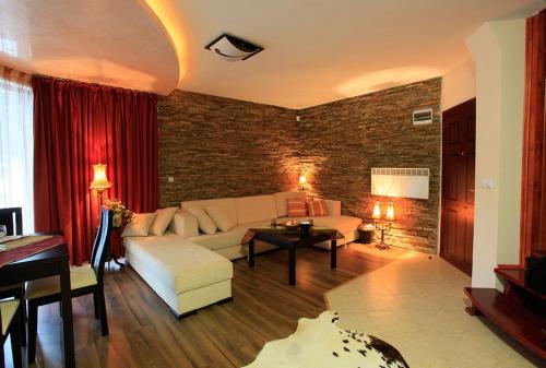 a living room with a white couch and a brick wall at Snow White's Secret Chalet in the Forest in Pamporovo