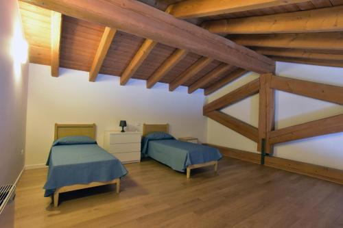 two beds in a room with wooden ceilings at Tenuta Monterosso in Feriole