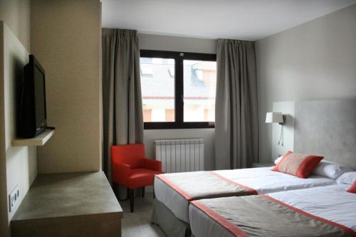 a hotel room with two beds and a red chair at Hotel & Spa Real Jaca in Jaca