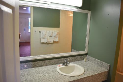 a bathroom with a sink and a mirror and towels at Red Carpet Inn & Suites Culpeper in Culpeper