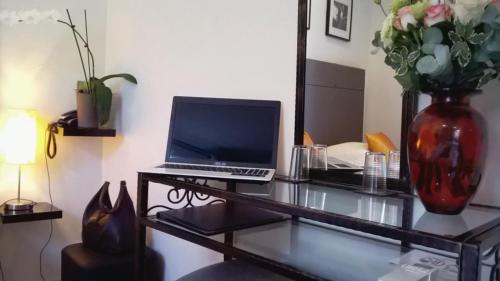 a desk with a laptop and a vase of flowers at Le Panoramic Boutique Hôtel in Nice
