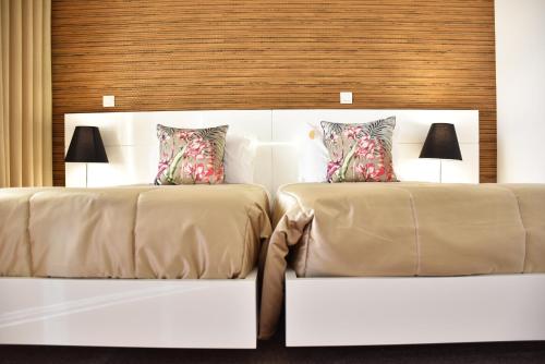 two beds in a hotel room with two lamps at Hotel Rural Quinta das Quintães in Penafiel