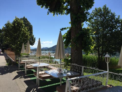 a row of tables with umbrellas on a sidewalk at Promenaden-Strandhotel Marolt in Sankt Kanzian