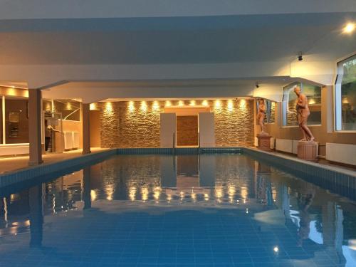 a man standing next to a swimming pool at night at Promenaden-Strandhotel Marolt in Sankt Kanzian