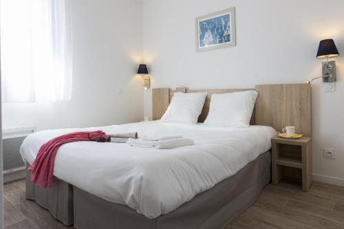ein Schlafzimmer mit einem großen Bett mit weißer Bettwäsche in der Unterkunft Résidence Prestige Odalys Le Domaine des Pins in Noirmoutier-en-l'lle