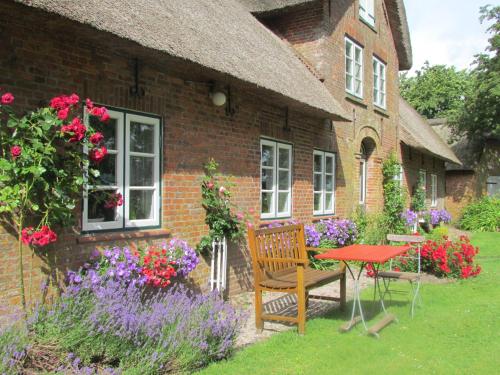 una casa con una mesa, un banco y flores en Historischer Davidshof - Mit dem Rad die Nordseehalbinsel erkunden, en Oldenswort