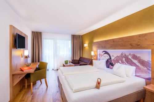 a hotel room with a large bed and a desk at Biohotel Leutascherhof in Leutasch