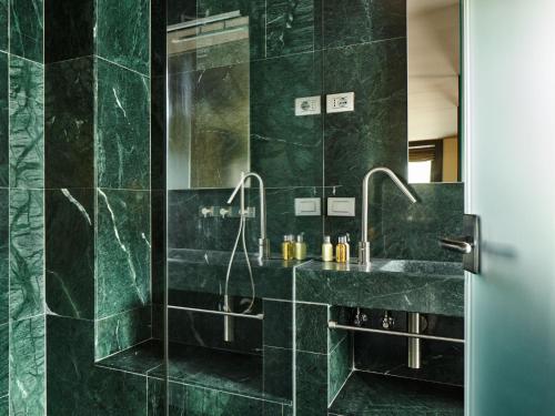 un bagno verde con lavandino e doccia di Albergo Diffuso Sauris in Lateis a Lateis