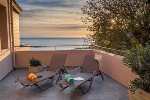 two chairs on a balcony with a view of the ocean at Stella in the Village Suites in Plakias
