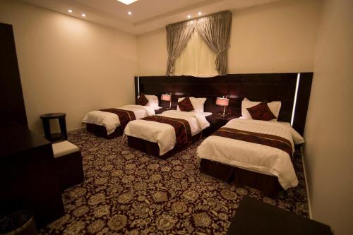 a hotel room with three beds in a room at Elaf Aparthotel in Buraydah