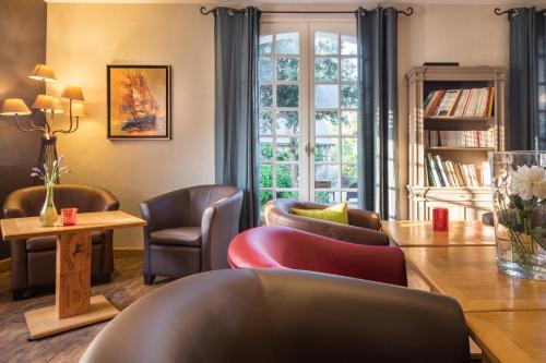 a living room with chairs and a table and a window at Logis L'Ermitage Hôtel & Restaurant in Saulges