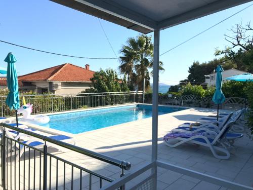 a patio with a swimming pool and two lawn chairs at Hotel Bavaria Trogir in Trogir