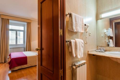 La salle de bains est pourvue d'un lavabo et d'un lit dans la chambre. dans l'établissement Hotel Victoria, à Linares