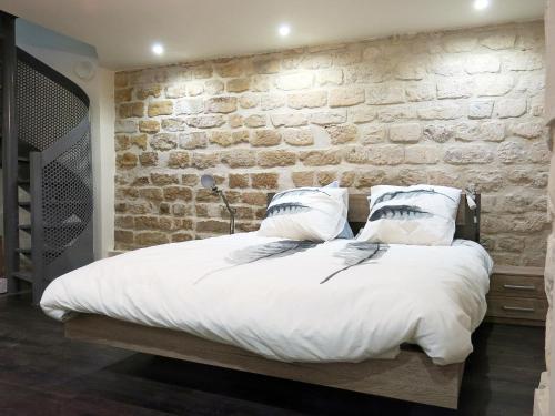 - une chambre avec un lit et un mur en pierre dans l'établissement Loft Marais Sébastopol CityCosy, à Paris